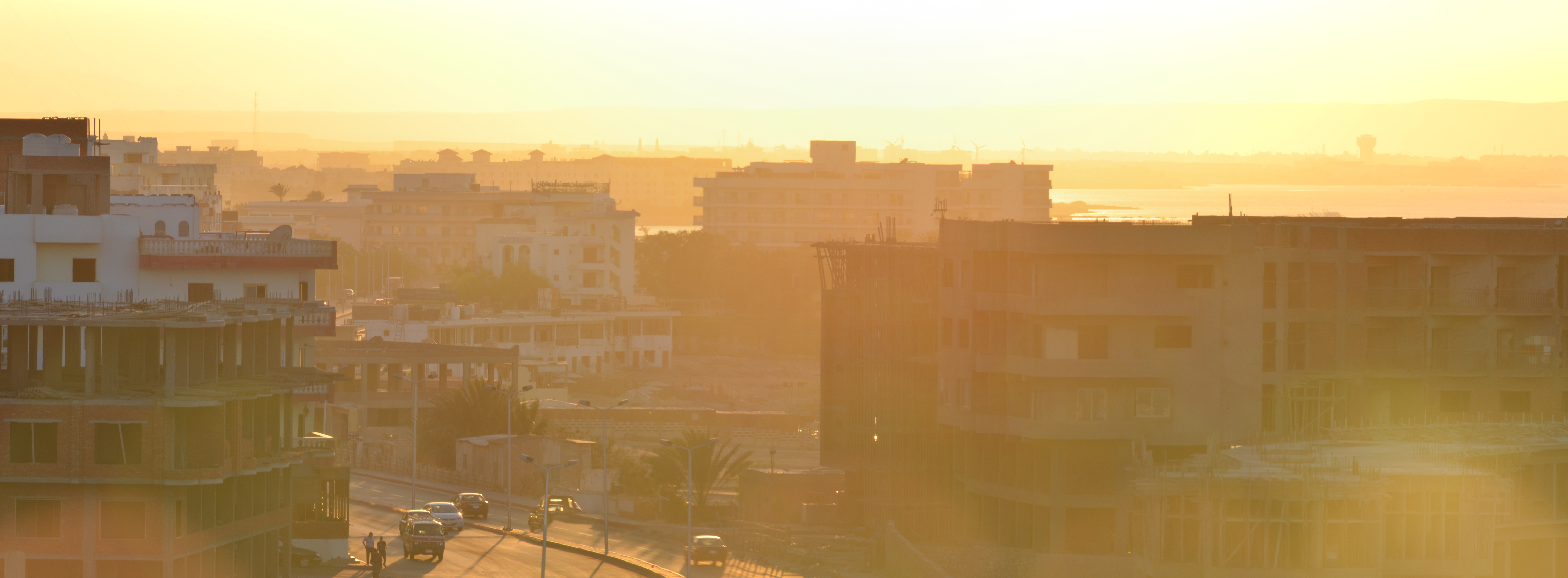 Paysage urbain sous une lumière dorée intense au coucher de soleil, créant une atmosphère chaude et brumeuse.