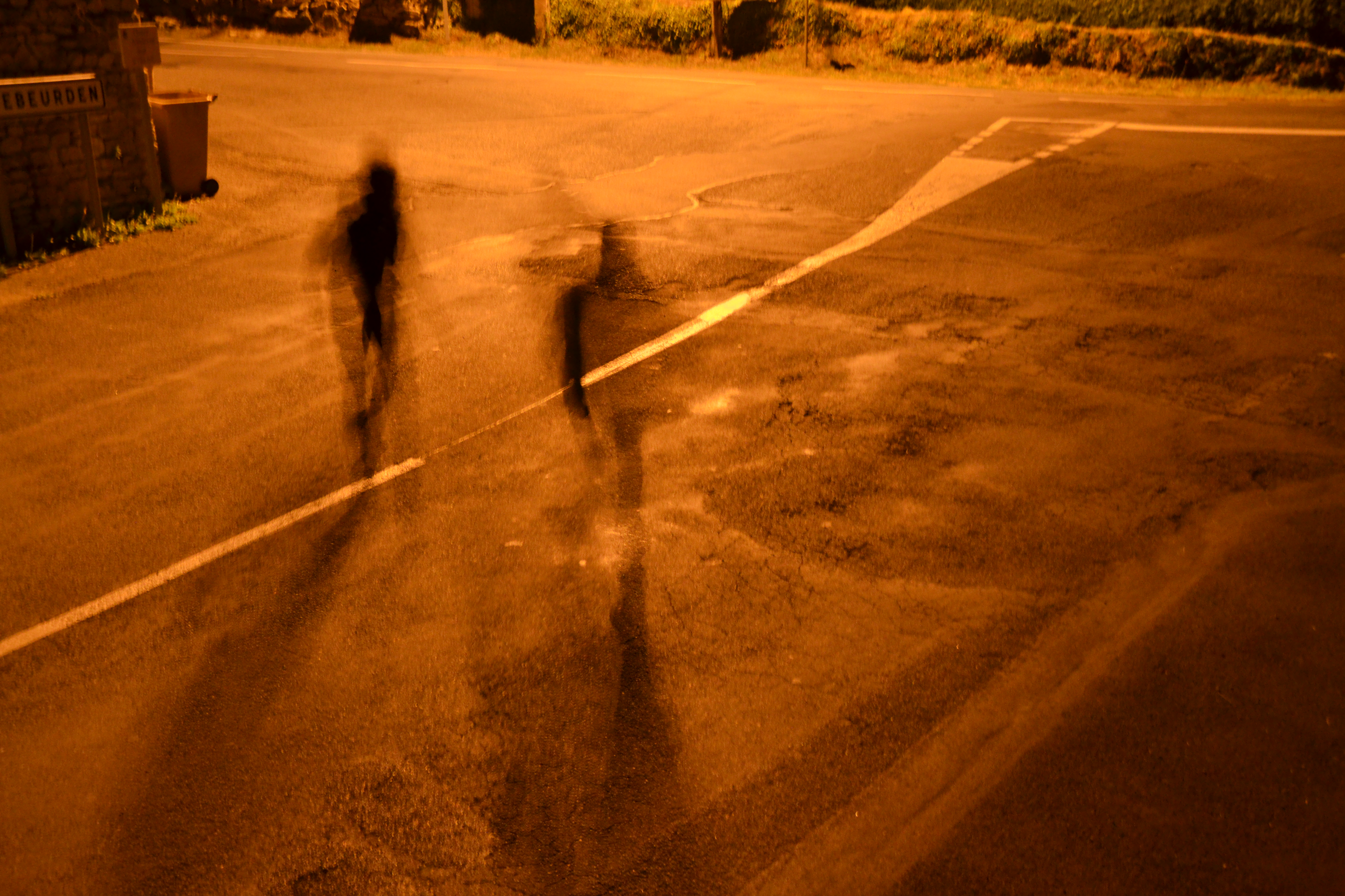 Deux silhouettes floues en mouvement sous un éclairage orangé nocturne.