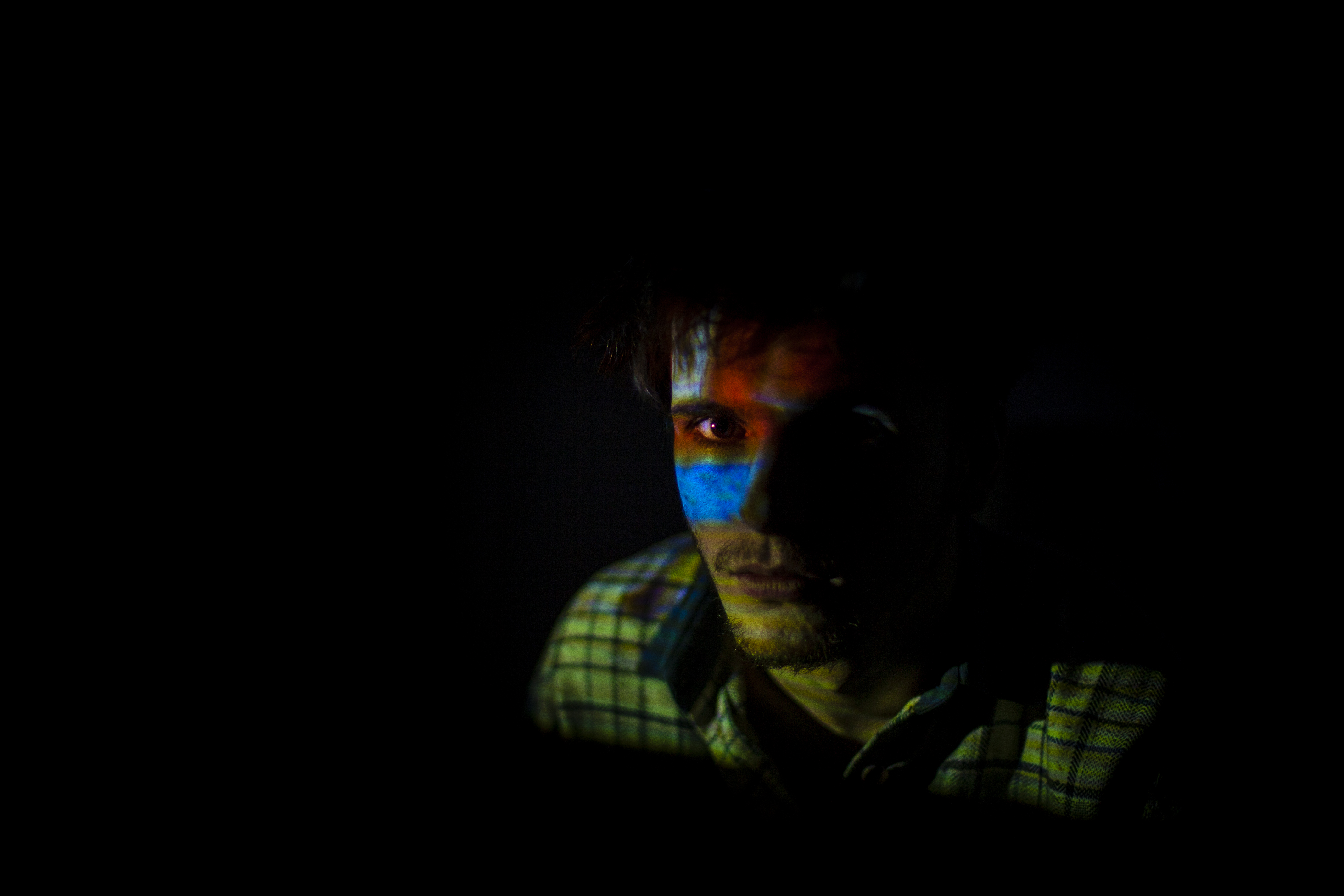 Visage d'une personne éclairé par la projection d'un jeu vidéo rétro, créant un effet visuel intense et coloré.