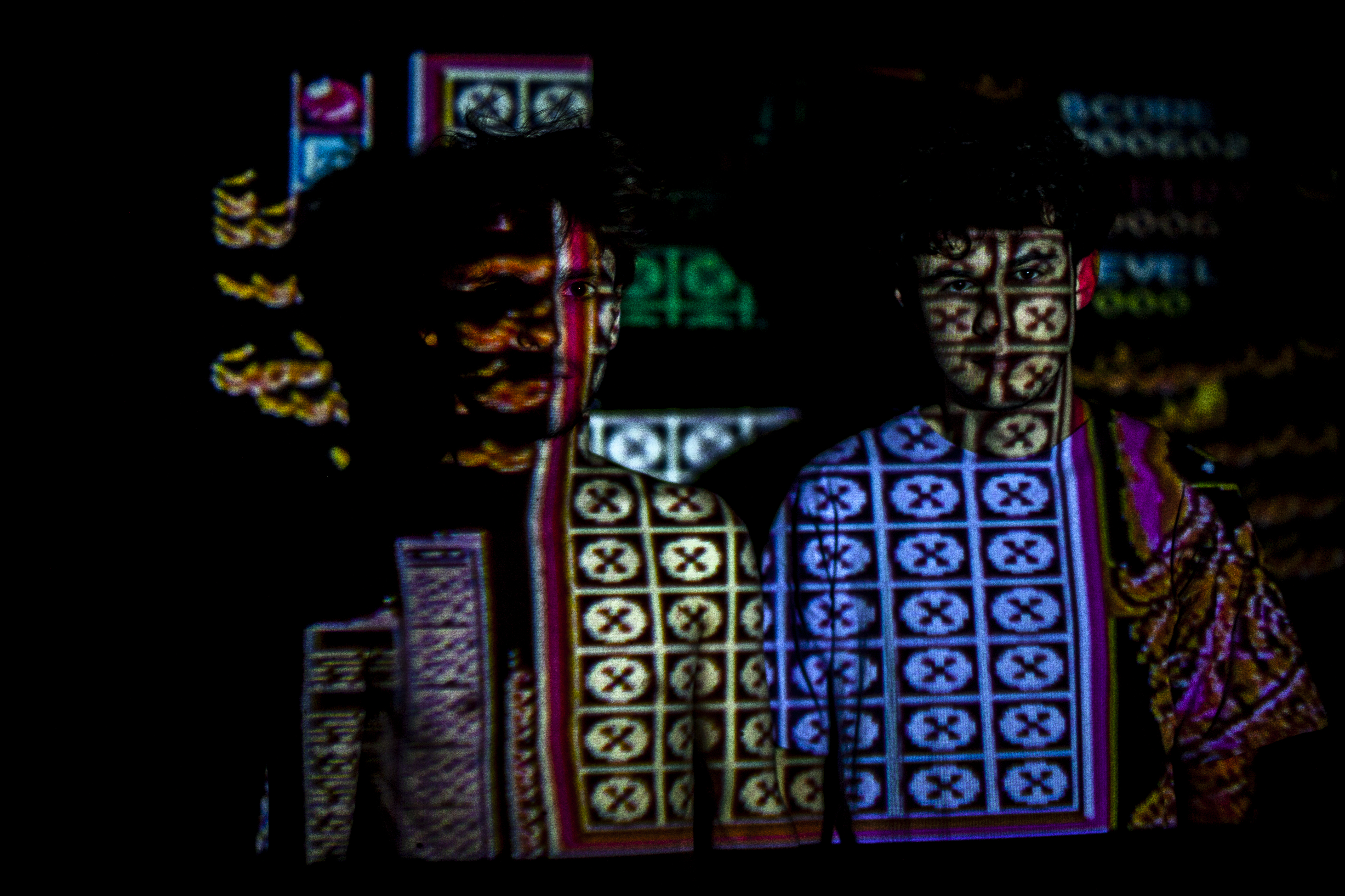 Visage d'une personne éclairé par la projection d'un jeu vidéo rétro, créant un effet visuel intense et coloré.